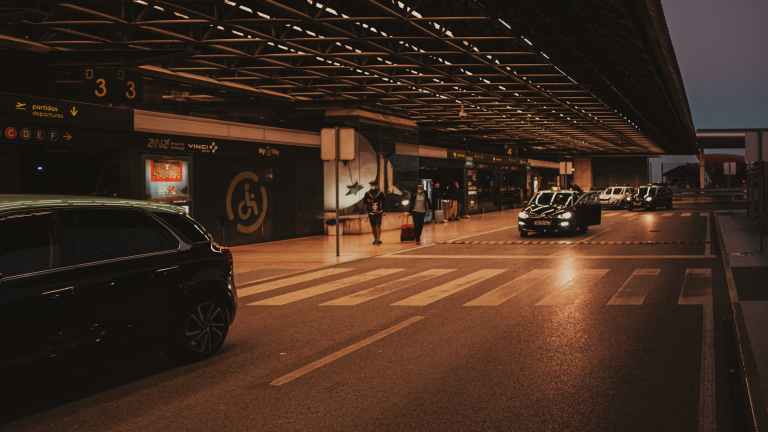 Passengers with luggage at airport shuttle pickup zone at night in Vienna