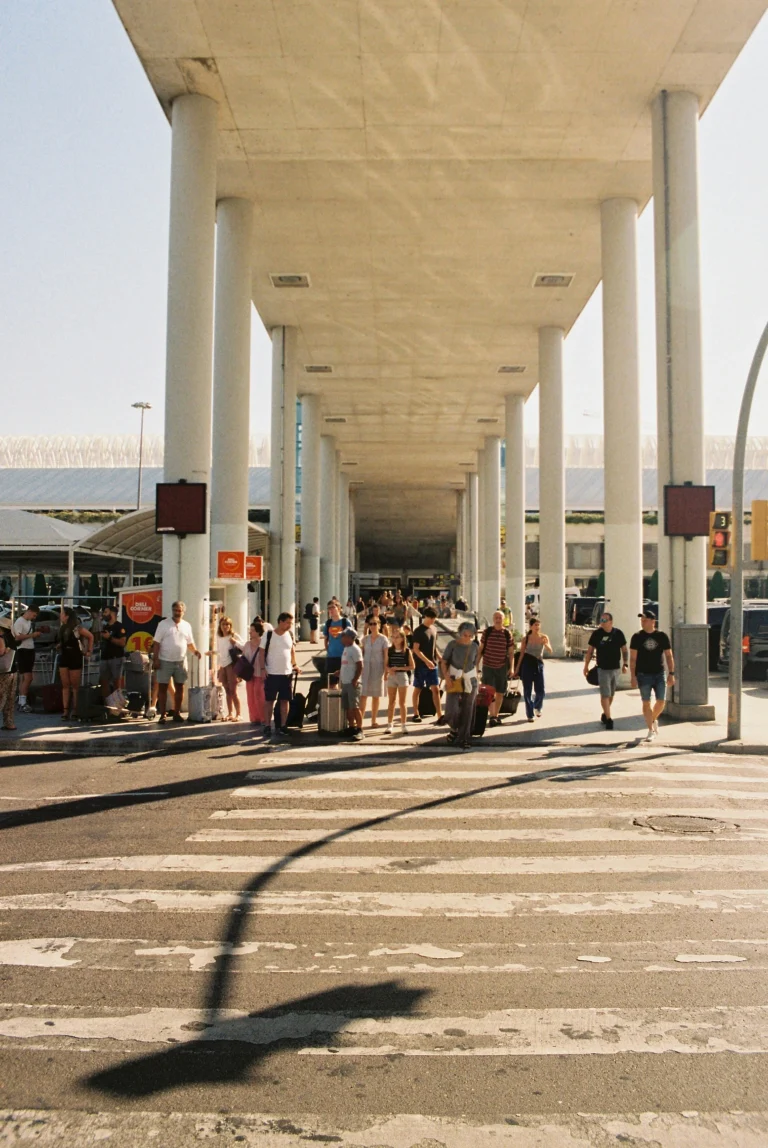Travelers with luggage at Vienna airport taxi pickup area during the day