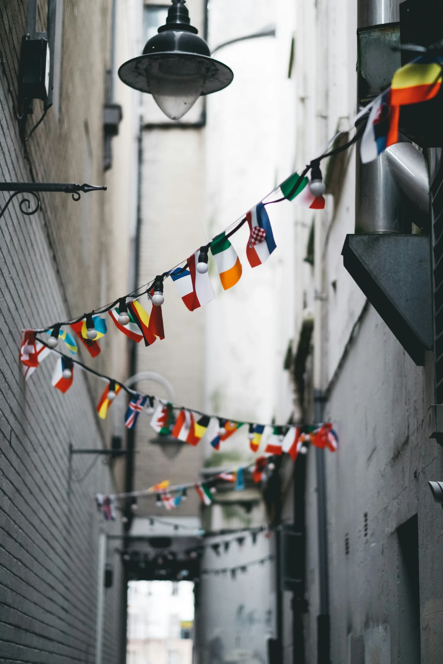String of international flags hanging across a narrow city alleyway