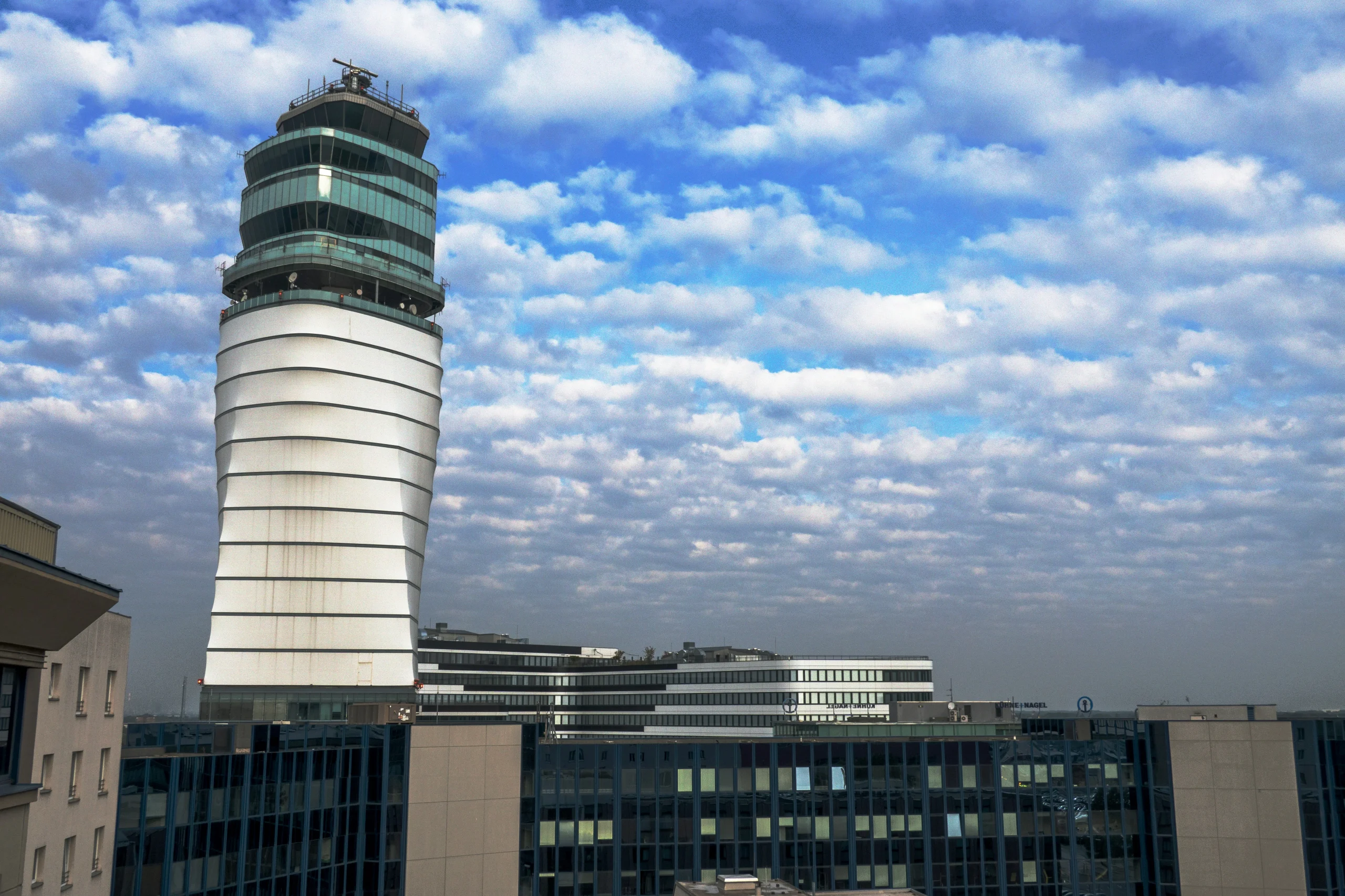 Control tower of Vienna International Airport under a partly cloudy sky