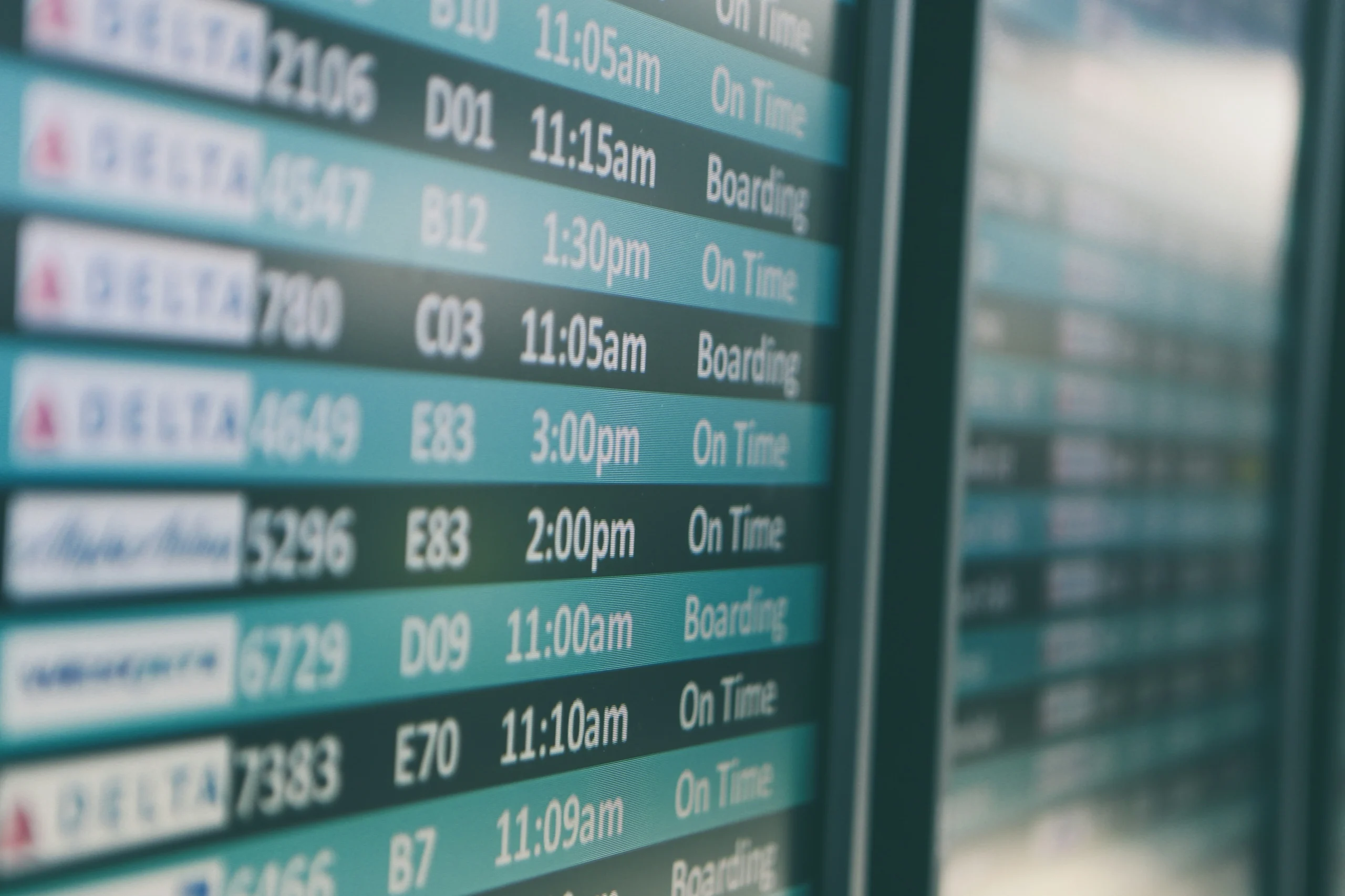 Close-up of airport departure board with flight times and boarding statuses